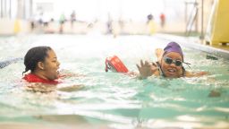 Bradlin Jacob-Simms swims with instructor Mahoganny Richardson at the YMCA’s O’Fallon Park Rec Complex on March 18, 2025, in St. Louis. She is learning to swim as an adult, while her daughter, Karter, competes on the Makos Swim Team. Richardson also has a daughter on the team. (Michael B. Thomas for KFF Health News)