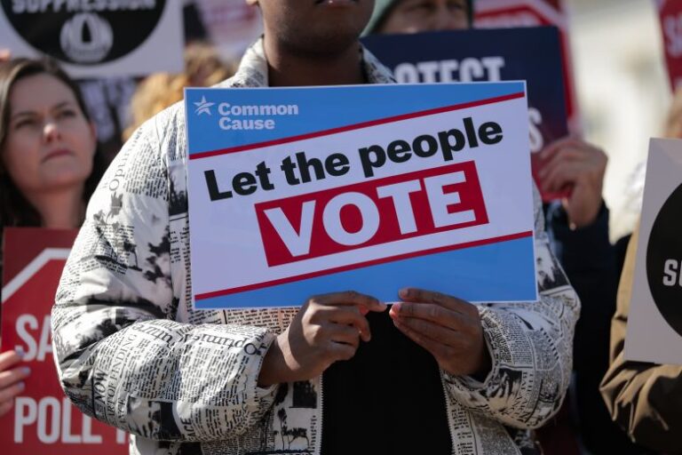 Attendees hold signs advocating for voting rights and against the SAVE America Act at a rally to outside the US Capitol on March 18, 2026, in Washington, DC.
