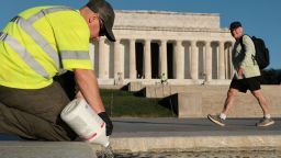 A U.S. National Park Service worker dumps bottles of hydrogen peroxide in the Lincoln Memorial Reflecting Pool as part of their effort to mitigate an algae bloom which followed the completion of recent renovations in Washington, D.C. on June 16, 2026.