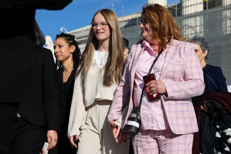 Becky Pepper-Jackson, 15, who competes in shot put and discus on her high school team, holds her mother's, Heather Jackson, hand outside the U.S. Supreme Court, in Washington, D.C. on January 13, 2026.
