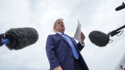 US President Donald Trump holds a printed-out article as he speaks to the members of the media after disembarking Marine One, before boarding Air Force One, at Joint Base Andrews, Maryland, August 14