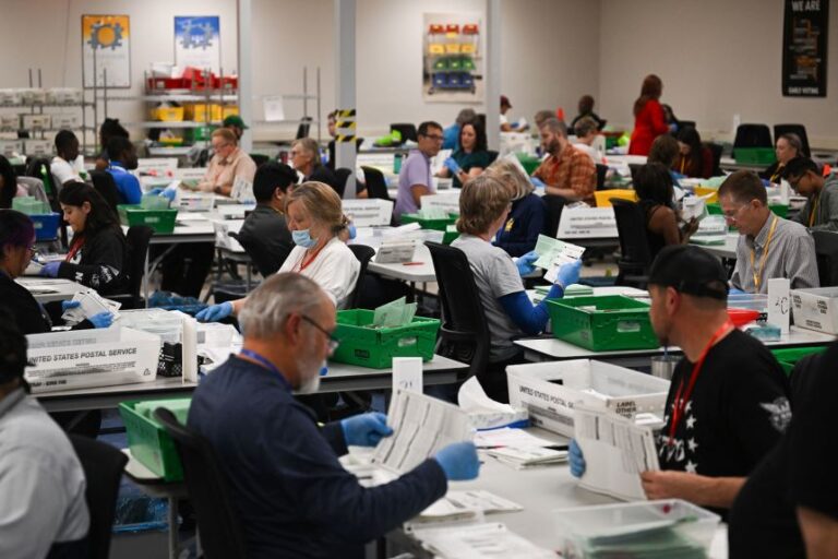 Pairs of election workers from different political parties open and inspect mail-in ballot envelopes containing voted ballots after they completed signature verification during processing inside the Maricopa County Tabulation and Election Center (MCTEC) on Election Day, November 5, 2024 in Phoenix, Arizona.