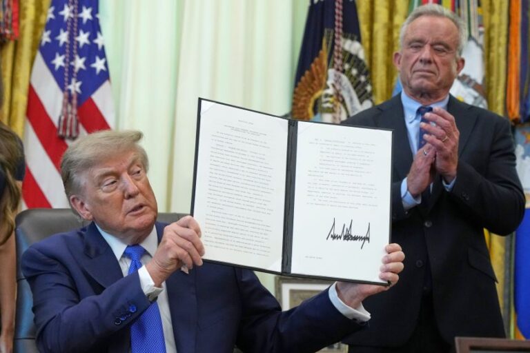 President Donald Trump holds a signed executive order about vaccines as Health and Human Services Secretary Robert F. Kennedy Jr. looks watches on August 10 in the Oval Office.