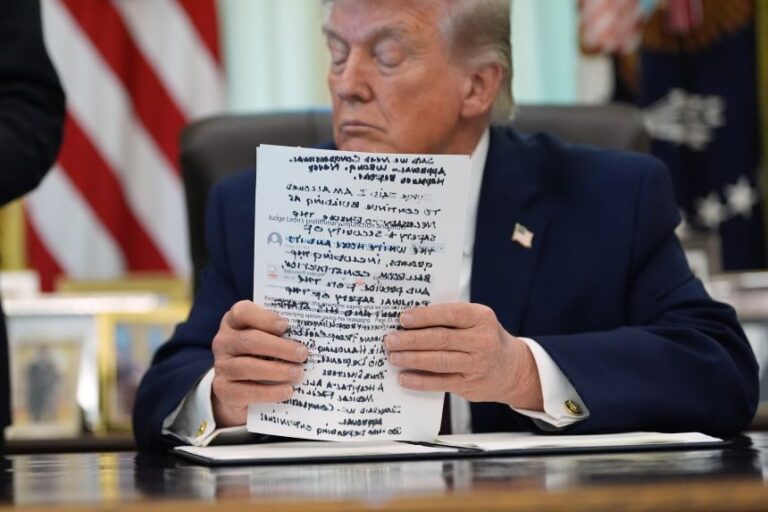 President Donald Trump holds papers in the Oval Office of the White House before signing an executive order in Washington DC on March 31.