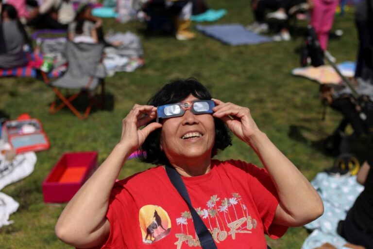 A woman tests her protective glasses ahead of a partial solar eclipse in April 2024 in New York City.