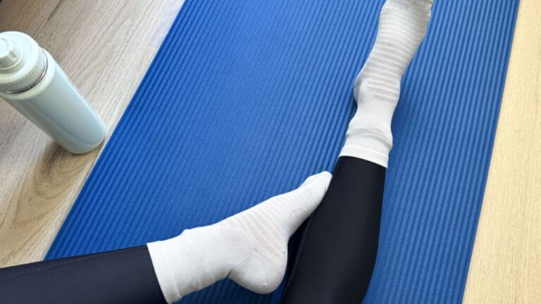 A person's feet on a blue yoga mat.