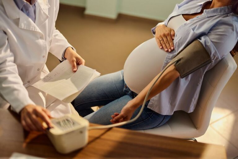 Unrecognizable pregnant woman having her blood pressure checked during an appointment at gynecologists' office.