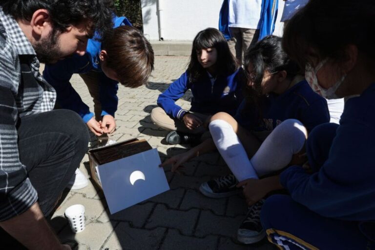 People observe a partial solar eclipse on a paper through a telescope in Ankara, Turkey, on October 25, 2022.
