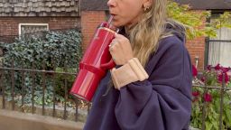 A woman drinking out of a Stanley tumbler wearing Bala Bangles.