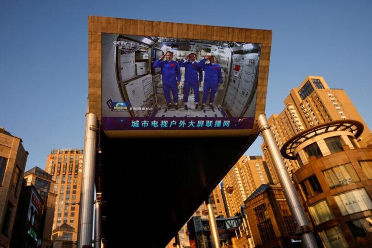At a shopping mall in Beijing, a giant screen shows taikonauts saluting inside the Tianhe core module of China's space station in 2021.