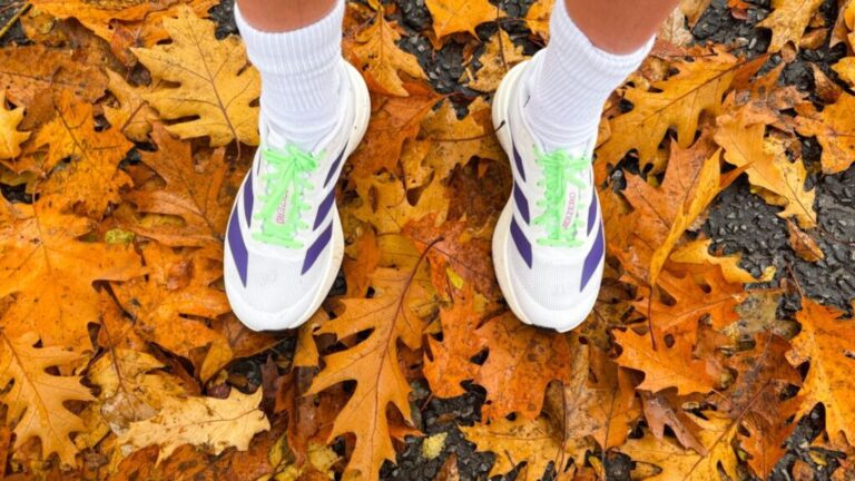 A person wearing Adidas Adizero EVO SL running shoes on top of leaves.