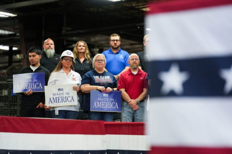 Employees of the Milbank Manufacturing Company hold signs as US Sen. Eric Schmitt of Missouri speaks during an event with US Vice President JD Vance at the facility on May 18 in Kansas City, Missouri.