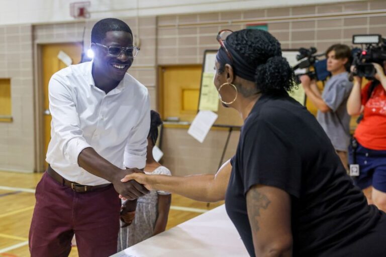 Crowley shakes hands with an election official at a polling location inside Milwaukee German Immersion School on Tuesday.