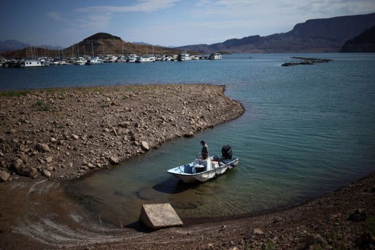 A man wades his boat into the receding shoreline of Lake Mead, the largest reservoir in the United States by water capacity, highlighting the long-term effects of drought and water demand on the Colorado River system, near Boulder City, Nevada, on August 12.