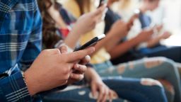 Close Up Of A Line Of High School Students Using Mobile Phones