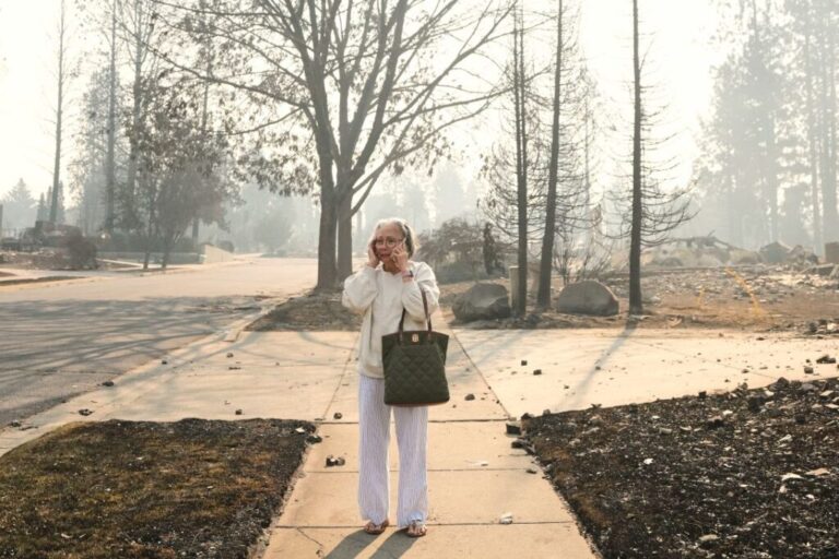 Miriam Sim, 76, reacts as she walks through the burned remains of her neighborhood after a wildfire hit the northern part of Spokane, Washington, on Monday, Aug. 3.