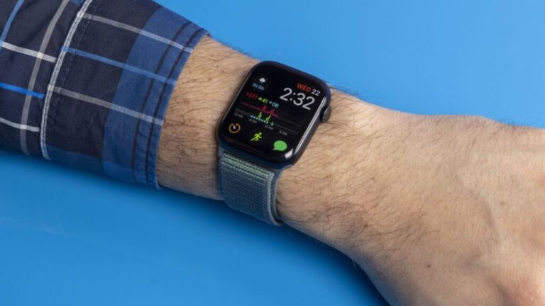 The Apple Watch is on a wrist, it's showing time and many icons, plus a chart of fitness data.