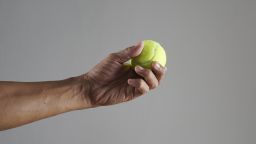 A hand holds a tennis ball.