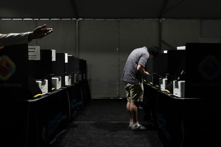 A voter looks at his phone while casting a ballot at a vote center set up in a tent in Las Vegas in June.
