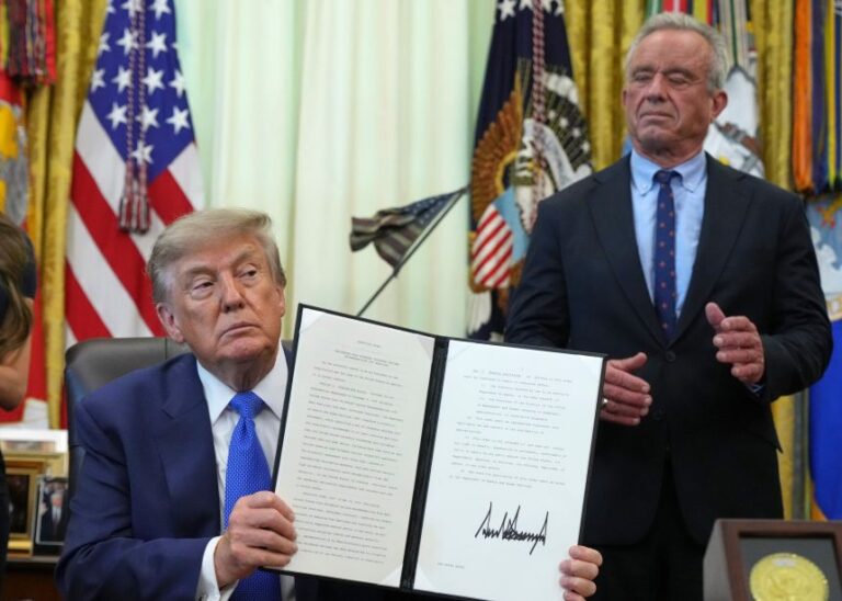 President Donald Trump holds an executive order about vaccines as US Health and Human Services Secretary Robert F. Kennedy Jr. looks on Monday, August 10, in the Oval Office.