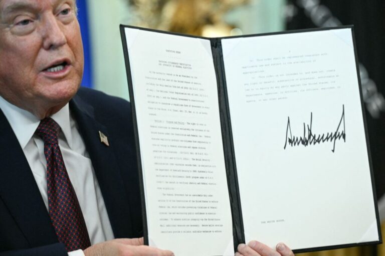 President Donald Trump displays an executive order he signed cracking down on mail-in voting, ahead of midterm elections, in the Oval Office of the White House on March 31.