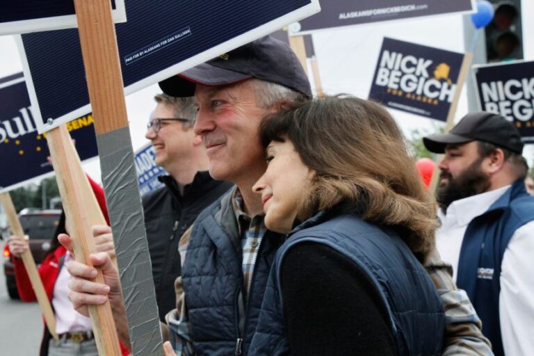 Sen. Dan Sullivan embraces his wife Julie Fate Sullivan while waving signs at an intersection in Anchorage on Tuesday.