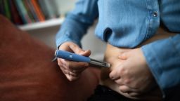 A person injects themself with a GLP-1 drug.