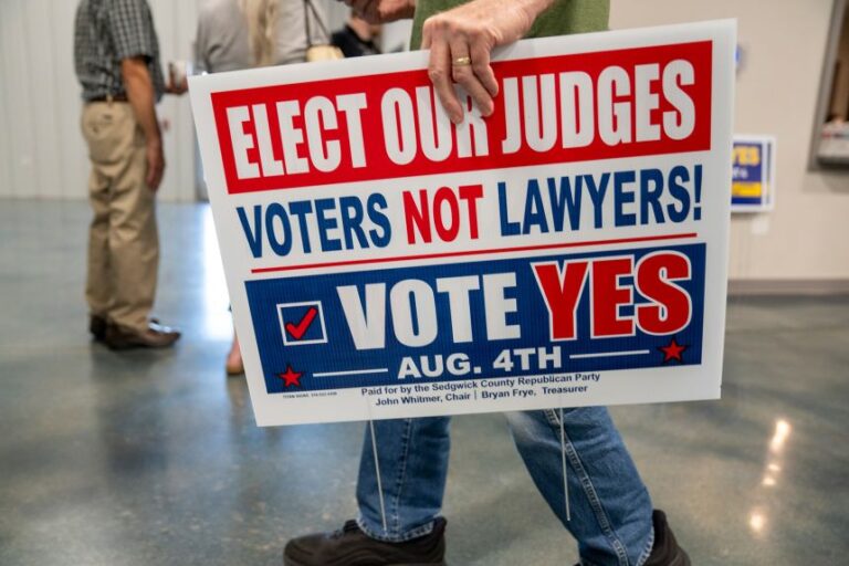 A voter carries a yard sign out of an event that encouraged voters to approve SCR 1611 in Newton, Kansas, on July 16.