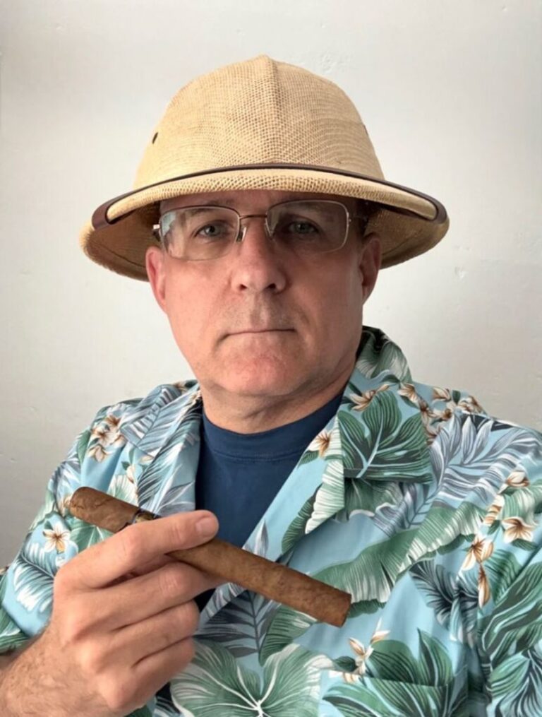 Paul Whelan wearing a Hawaiian shirt, holding a cigar.