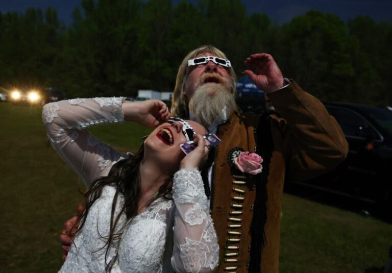 A newly married couple views the eclipse after a <a href=