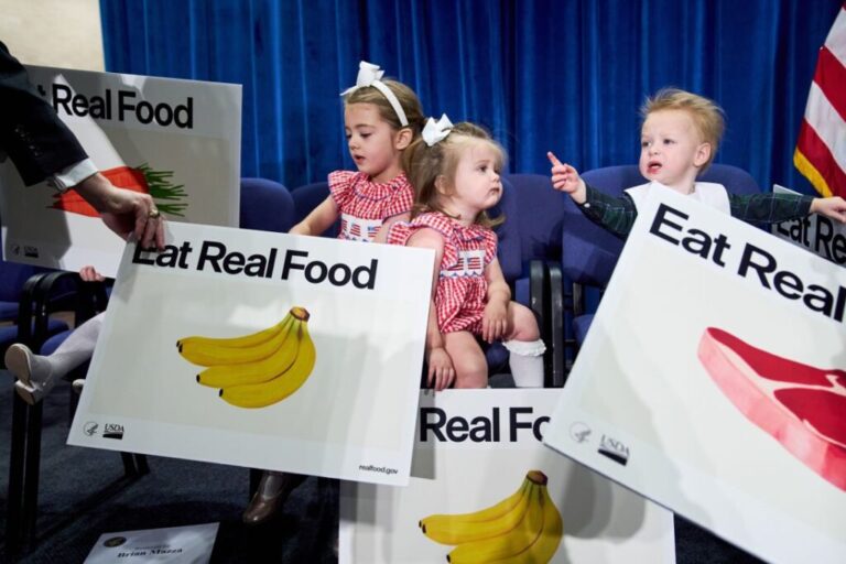 Children hold signs at an event about nutrition guidelines with Health and Human Services Secretary Robert F. Kennedy Jr.