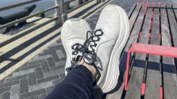 White sneakers on feet with wooden deck in the background