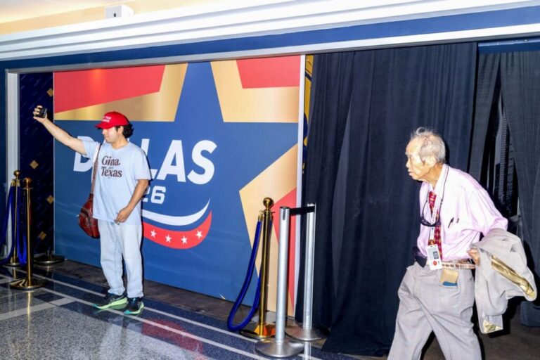 An attendee takes a selfie near a convention logo.