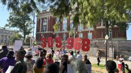 In this photo taken with a smartphone, people opposing a congressional redistricting plan rally outside the Missouri Supreme Court in Jefferson City, Mo., Wednesday, Sept. 2, 2026, while displaying the number of petition signatures submitted seeking a statewide vote on the measure. (AP Photo/David A. Lieb)