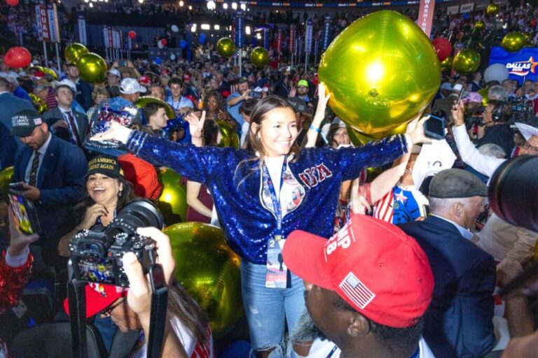 A young woman takes a picture with balloons as they fall from the ceiling on Thursday.