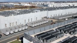An aerial view shows cooling vent fans on the roof next to generators on the lower level of a Digital Realty data center in Ashburn, Virginia on November 12, 2025. Data centers are the physical infrastructure that make our digital lives possible, yet most people have never seen one up close or understand how they operate. Roughly 12,000 data centers are in operation in the world, with about half in the US, according to Cloudscene, a data center directory. (Photo by ANDREW CABALLERO-REYNOLDS / AFP via Getty Images)