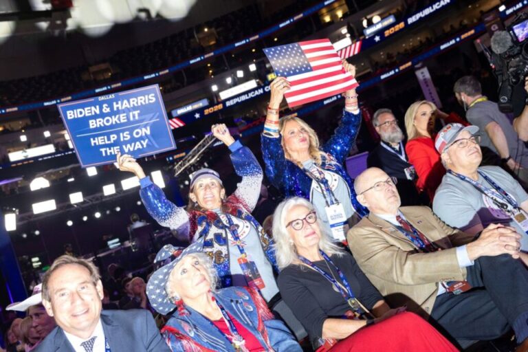 Attendees hold up signs and cheer on the floor as the convention kicks off.
