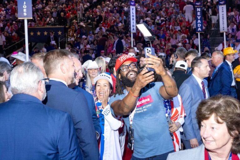 People take pictures and find their seats on the convention floor.