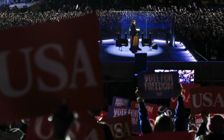 Supporters hold up signs as Democratic presidential nominee former US Vice President Kamala Harris looks back at them during a campaign rally in Philadelphia, Pennsylvania, on November 4, 2024.
