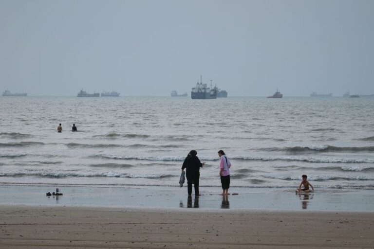 People spend time at a beach as commercial vessels are anchored in the Strait of Hormuz off Bandar Abbas, Iran, on Wednesday, Sept. 2.
