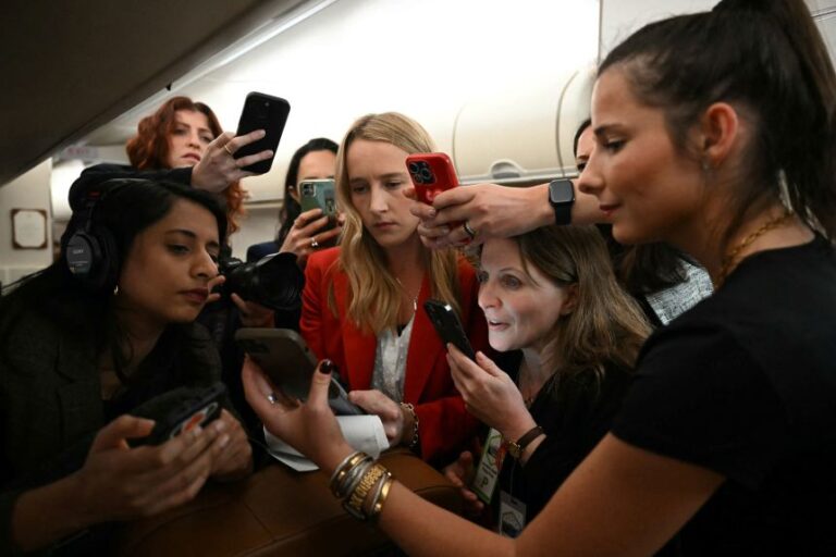 CNN's Kit Maher, center, and other members of the press look at a statement from White House Press Secretary Karoline Leavitt about a reported suspicious package on President Donald Trump's route to Palm Beach International Airport, aboard Air Force One on January 11.