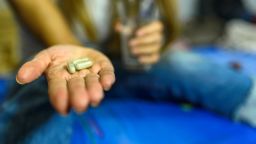 Worried sick young woman holding pill glass of water at home, teen feels ill taking medicine, depressed girl about to take antidepressant pill, emergency contraceptive, painkiller for painful periods