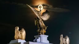 The moon rises behind a winged statue atop a mockup of President Donald Trump's proposed Triumphal Arch at the Great American State Fair on the National Mall in June in Washington, DC.