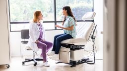 Female doctor talking with young woman in exam room