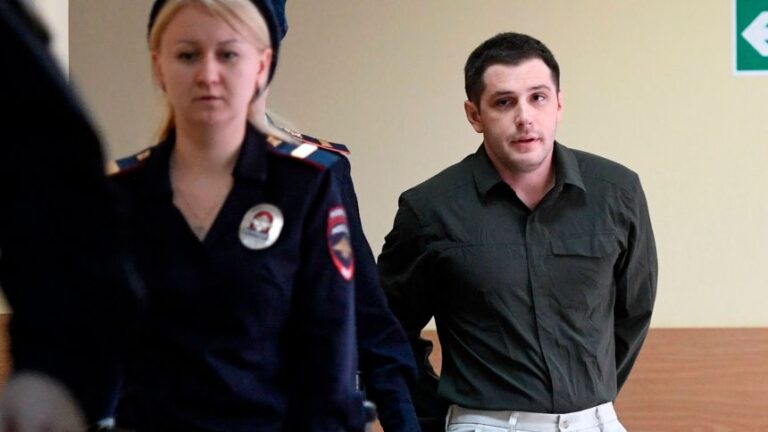 Police officers escort US ex-marine Trevor Reed, charged with attacking police, into a courtroom prior to a hearing in Moscow on March 11, 2020.