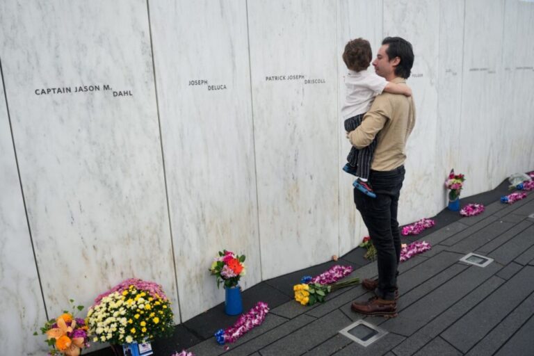 Ryan Gould, grandson of Flight 93 victim Patrick Joseph Driscoll, holds his son next to the Wall of Names at the Flight 93 National Memorial near Shanksville, Pennsylvania.