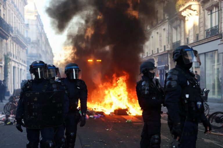 A fire burns as police officers in riot gear stand guard in Paris on Sunday.