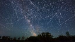 This depicts the satellite-filled sky that is now a reality and getting more crowded every week! This adds together exposures taken over just 30 minutes on an early June night when, from my latitude of 51° N satellites even in low Earth orbit are lit all night by sunlight. Many of the parallel streaks heading generally horizontal west to east (right to left) may be from groups of SpaceX Starlinks. Others traveling vertically north-south are more likely from Earth observation satellites. There is at least one natural streak in the image — a meteor at centre, caught by chance on one frame. It appears as a colored and tapered streak. Other uniform undashed streaks may be from high-altitude satellites moving much more slowly. By comparison, most satellites appear as dashed lines because the image is a blend of many 2-second-long exposures with a gap of one second between exposures when the camera shutter was closed. So the motion of the satellites and image stacking turns them into dashes. The longer the dashes, the faster the satellite is traveling, with the fastest satellites being the lowest. This is looking due south and all the trails disappear low in the south above the trees, as that's where the Earth's shadow is, even on this June night. So the satellites aren't lit when they are in that small part of the sky. They emerge from the shadow heading north and disappear into the shadow heading south. The shadow creates the obvious boundary of where satellite trails are visible. At other times of the year low-orbit satellites are visible only after sunset or before sunrise, especially from lower latitudes. But not near summer solstice, and from higher latitudes. The field of view is about 100° by 75°. (Photo by: Alan Dyer/VWPics/Universal Images Group via Getty Images)
