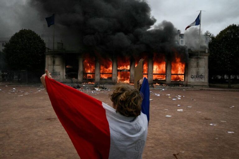 A protester wrapped in a French national flag stands in front of Lyon's tourism office on Saturday.