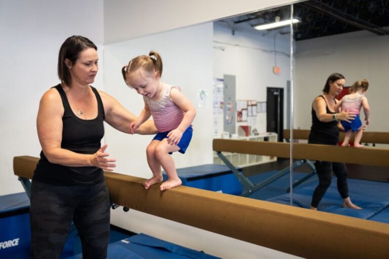Emily Marris, 51, helps her daughter Brooklyn “Brookie” Marris, 2, balance while playing at GForce Gymnastics & Parkour in Murrieta, California on March 27, 2026. In 2025, Brooklyn was hospitalized and went into cardiac arrest three times after consuming unpasteurized goat milk.